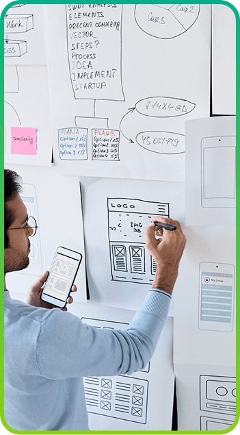 Person sketching wireframes on paper taped to the wall