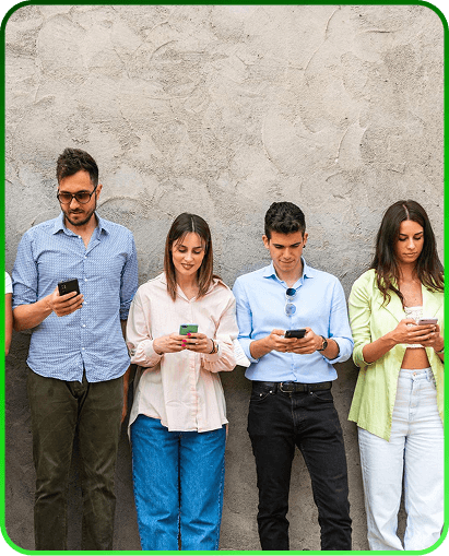 Four young users leaning against a wall looking at their mobile phones